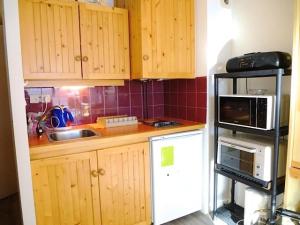 a small kitchen with wooden cabinets and a microwave at Résidence Lienz - Appartement avec terrasse exposé Sud, proche du centre de Barèges MAE-8454 in Barèges