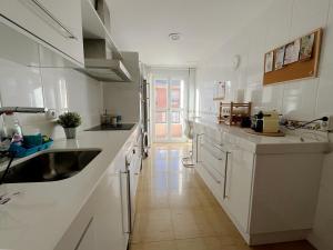 una cucina bianca con lavandino e armadietti bianchi di Dúplex Valle del Silencio a Ponferrada