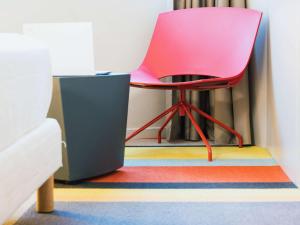 a pink chair sitting on a colorful rug in a room at ibis Styles Lyon Sud Vienne in Chasse-sur-Rhône