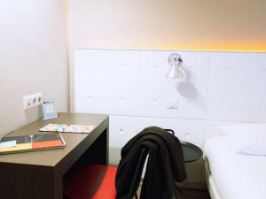 Dormitorio con escritorio, cama y lámpara en ibis Styles Lyon Sud Vienne en Chasse-sur-Rhône