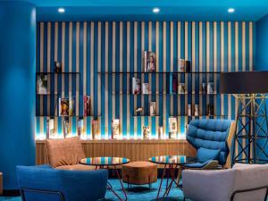 a living room with blue chairs and a book shelf at ibis Paris CDG Airport in Roissy-en-France