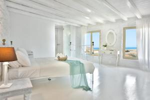 a white bedroom with a bed and a view of the ocean at Mykonos Dream Villas in Ftelia