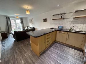 a kitchen with a sink and a living room at Spacious 2 Bed 2 Shower Apartment in Crewe