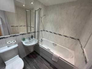 a bathroom with a tub and a toilet and a sink at Spacious 2 Bed 2 Shower Apartment in Crewe
