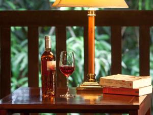 琅勃拉邦3 Nagas Hotel Luang Prabang - MGallery Collection的桌上的一瓶酒和一杯酒