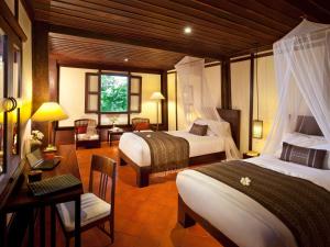 a hotel room with two beds and a desk and a room at 3 Nagas Luang Prabang - MGallery Hotel Collection in Luang Prabang