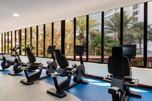 a row of treadmills in a gym with a large window at The Diplomat Radisson Blu Residence in Manama