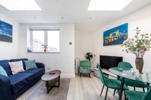 uma sala de estar com um sofá azul e uma mesa em Cosy 1 Bed apartment with FREE PARKING close to Underground station zone 2 for quick access to Central London up to 5 guests em Londres