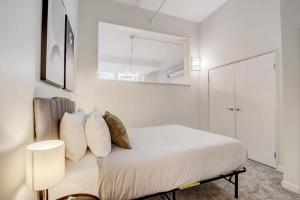 um quarto branco com uma cama com lençóis e almofadas brancos em CozySuites - 1BR with Direct Skybridge Access #2 em Indianápolis