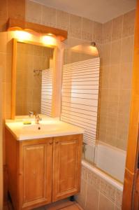 een badkamer met een wastafel, een spiegel en een bad bij Résidence Gentiane Hameau De La Vallee D'or - 2 Pièces pour 4 Personnes 74 in Valloire