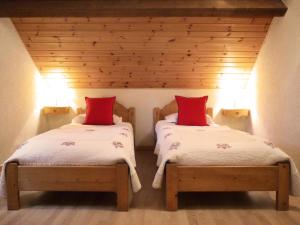 a bedroom with two beds with red pillows at Résidence Les Fermes Du Planet - Pièces 74 in Valloire