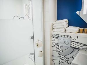 a bathroom with a shower with a toilet and towels at ibis budget Dijon Saint Apollinaire in Saint-Apollinaire +29 photos