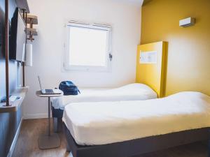 a room with two beds and a laptop on a table at ibis budget Dijon Saint Apollinaire in Saint-Apollinaire