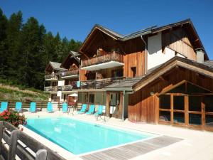 une maison avec une piscine en face de celle-ci dans l'établissement Chalet La Combe D Or - Chalets pour 6 Personnes 094, à Le Mélézet