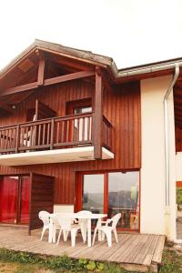 a deck with white tables and chairs on a house at Chalet La Combe D Or - Chalets pour 6 Personnes 094 in Le Mélézet