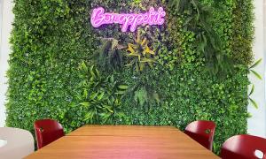 een groene muur met een houten tafel en rode stoelen bij Campanile Lyon Sud Feyzin in Feyzin