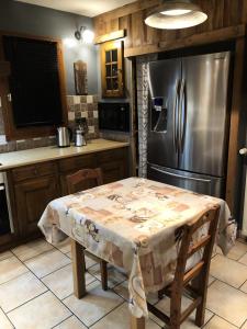 a kitchen with a table and a stainless steel refrigerator at Chalet Colenfrey - Chalets pour 10 Personnes 14 in Valloire