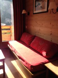 a bed with red pillows in a room with a window at Les Chalets Valoria - 2 Pièces pour 4 Personnes 44 in Valloire