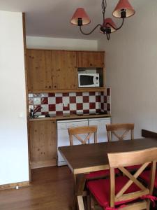een keuken met een tafel met stoelen en een magnetron bij Les Chalets Valoria - 2 Pièces pour 4 Personnes 44 in Valloire