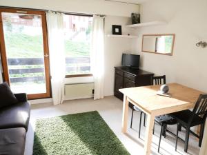 una pequeña sala de estar con mesa y TV en Résidence Plan Soleil - Studio pour 4 Personnes 64, en Valloire