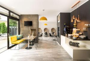 a lobby with a dining area and a bar with yellow chairs at Arthotel ANA Gold in Augsburg