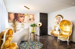 a bathroom with a tub and a chair and a desk at Arthotel ANA Gold in Augsburg