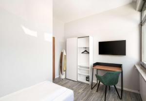 a bedroom with a bed and a desk and a tv at Arthotel ANA Gold in Augsburg