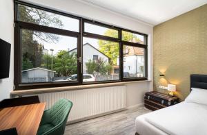 a bedroom with a bed and a large window at Arthotel ANA Gold in Augsburg +77 photos