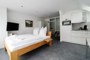 a bedroom with a large white bed and a kitchen at Ferienwohnung "Hygge" in Schluchsee in Schluchsee