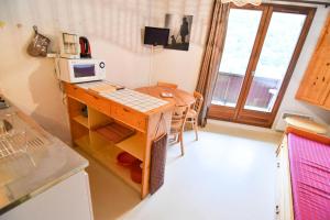 a small kitchen with a table and a microwave at Residence Le Thymel - Studio pour 3 Personnes 14 in Valloire