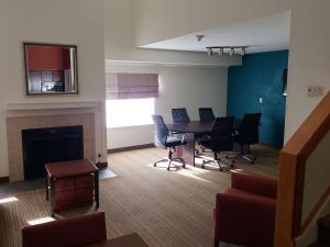 a living room with a table and chairs and a fireplace at Tysons Corner Suites, A Baymont by Wyndham in Vienna