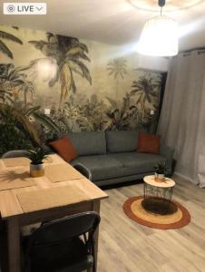 een woonkamer met een bank en een muurschildering van palmbomen bij Résidence Antigua - Studio pour 4 Personnes 984 in Le Barcarès
