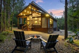 a cabin in the woods with two chairs and a fire pit at BRAND NEW!! Hochatown, Honey! Fire pit, hot tub, luxurious shower! in Broken Bow
