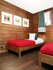 a bedroom with two beds with red sheets and a window at Résidence Les Fermes Du Planet - 4 Pièces pour 8 Personnes 94 in Valloire
