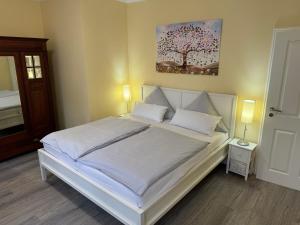 a bedroom with a white bed with a tree painting on the wall at Pension Auszeit in Bad Neuenahr-Ahrweiler