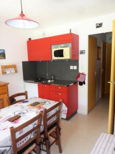 eine Küche mit roten Schränken und einem Tisch mit Stühlen in der Unterkunft Residence Le Thymel - 2 Pièces pour 4 Personnes 44 in Valloire