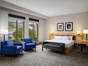 a hotel room with a bed and two blue chairs at The Waters Hot Springs, Tapestry Collection by Hilton in Hot Springs