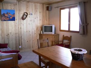 uma sala de estar com uma mesa e uma televisão em Chalet Les Aiguilles - Pièces 34 em Valloire