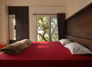 - une chambre avec un grand lit rouge et une tête de lit en bois dans l'établissement Camilla Living- A Luxury Escape by the Riverside!, à Guwahati