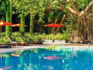 a swimming pool with two chairs and umbrellas next to it at Mercure Benidorm in Benidorm