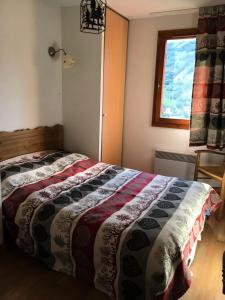um quarto com uma cama com uma colcha em Résidence Gentiane Hameau De La Vallee D'or - 2 Pièces pour 4 Personnes 84 em Valloire