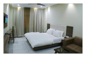 Hotel Grand Surya في Kodarma: غرفه فندقيه بسرير واريكه