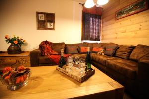 a living room with a couch and a table with wine bottles at Les Chalets D'adrien - Pièces 64 in Valloire