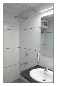 Baño blanco con lavabo y espejo en Hotel Grand Surya, en Kodarma