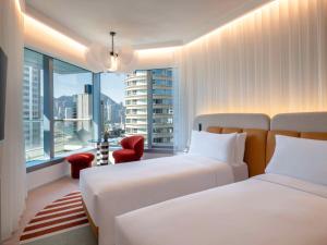 a hotel room with two beds and a large window at Mondrian Hong Kong in Hong Kong