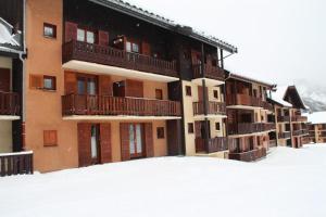 un edificio con balcones y nieve en el suelo en Résidence La Croix Du Sud - Studio pour 4 Personnes 44 en Valloire