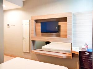 a room with a bed and a tv on a wall at Wikost Premiere Inn Mitra RedDoorz in Plelen