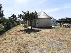 ein kleines Gebäude mit einem Baum auf einem Feld in der Unterkunft Résidence ILE DES PECHEURS - Maisons & Villas pour 6 Personnes 64 in Port Leucate