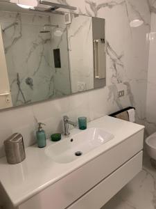 uma casa de banho branca com um lavatório e um espelho em On the top floor watching CityLife and MiCo em Milão