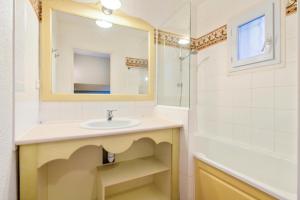 W łazience znajduje się umywalka, lustro i wanna. w obiekcie Les Issambres Corniche - maeva Home - Appartement 2 pièces 5 personnes Confort MAE-1353 w mieście Les Issambres